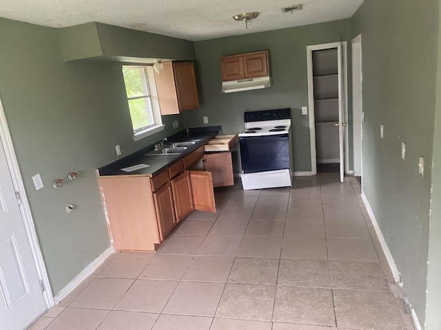 503 Willow St, Rosenberg, TX 77471 - kitchen with white electric stove, under cabinet range hood, light tile patterned floors, a textured ceiling, and dark countertops
