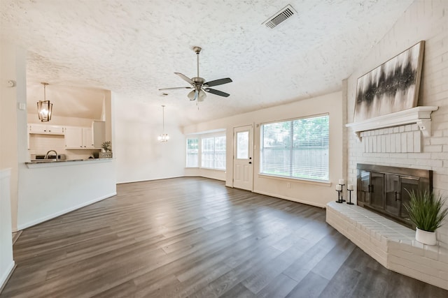 622 Magnolia Bend St, League City, TX 77573 - living room with a textured ceiling, ceiling fan, a brick fireplace, a chandelier, and dark wood-style flooring