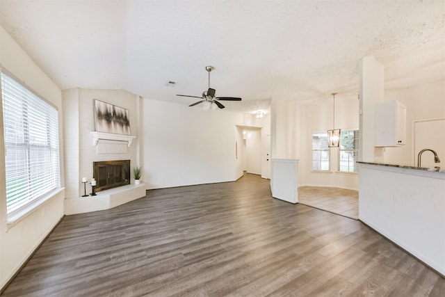 622 Magnolia Bend St, League City, TX 77573 - unfurnished living room with healthy amount of natural light, ceiling fan, a large fireplace, wood finished floors, and a textured ceiling