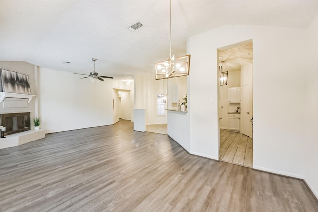 622 Magnolia Bend St, League City, TX 77573 - unfurnished living room featuring lofted ceiling, a ceiling fan, wood finished floors, a chandelier, and a fireplace