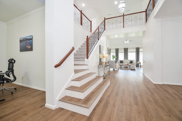 25619 Tower Side Ln, Katy, TX 77494 - staircase with wood finished floors, crown molding, ceiling fan, recessed lighting, and a high ceiling