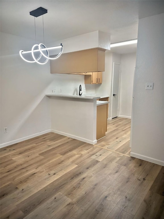 9350 Country Creek Dr Unit 58, Houston, TX 77036 - kitchen with a peninsula, light wood-type flooring, light countertops, hanging light fixtures, and a chandelier
