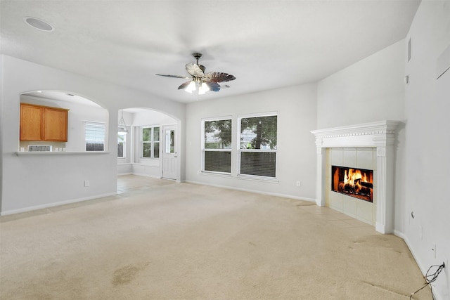 31 S Creekmist Pl, Conroe, TX 77385 - unfurnished living room featuring light carpet, ceiling fan, arched walkways, and a tiled fireplace