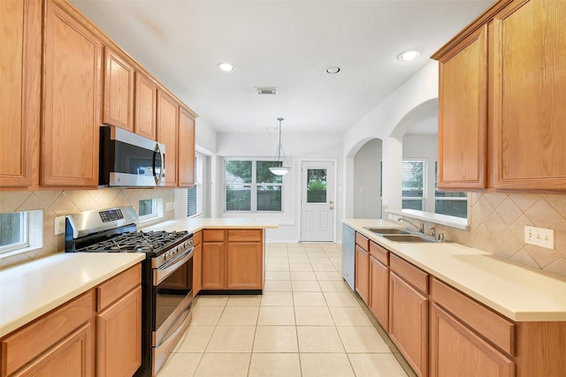 31 S Creekmist Pl, Conroe, TX 77385 - kitchen featuring stainless steel appliances, a peninsula, light tile patterned floors, arched walkways, and tasteful backsplash