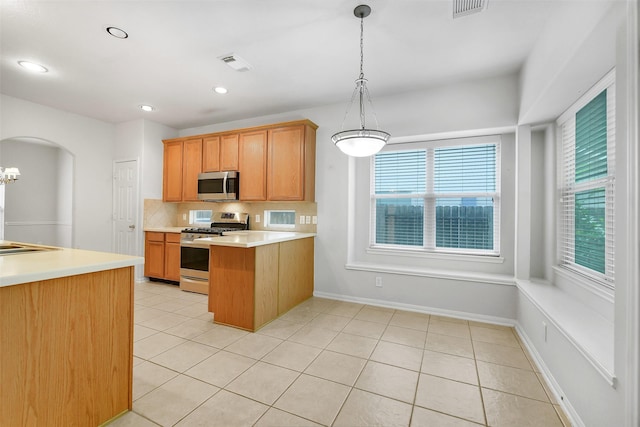 31 S Creekmist Pl, Conroe, TX 77385 - kitchen with stainless steel appliances, light tile patterned floors, decorative backsplash, light countertops, and a peninsula