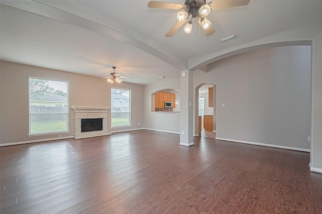 19819 Sternwood Manor Dr, Spring, TX 77379 - unfurnished living room featuring ceiling fan, dark wood-style floors, a fireplace with raised hearth, and arched walkways