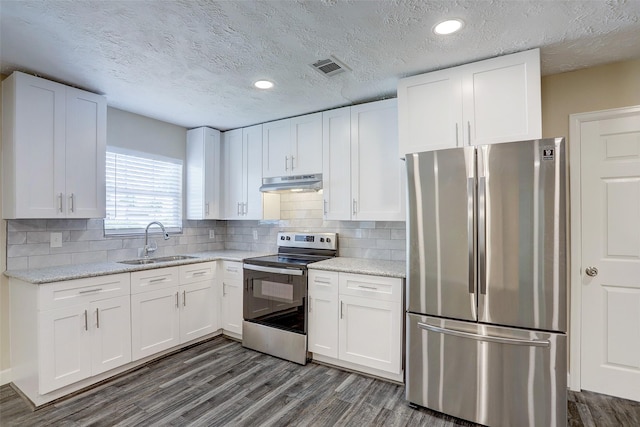 515 Main St, Pasadena, TX 77506 - kitchen with stainless steel appliances, under cabinet range hood, dark wood-style floors, white cabinetry, and a textured ceiling