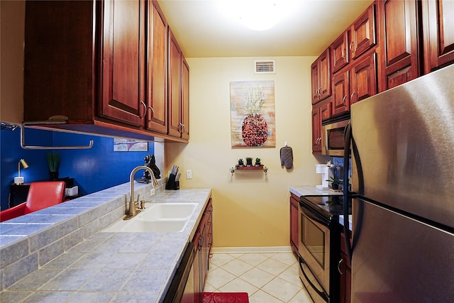 4004 Montrose Blvd Unit 45A, Houston, TX 77006 - kitchen featuring stainless steel appliances, tile counters, light tile patterned flooring, and dark brown cabinets