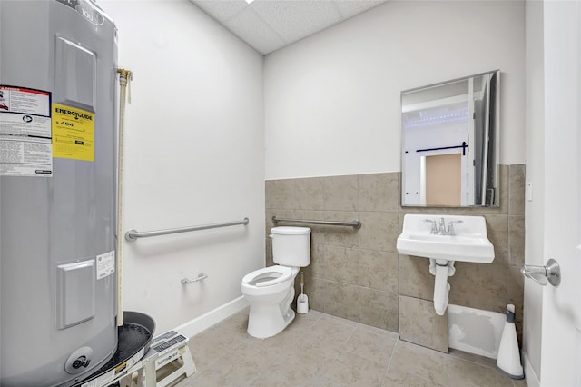 440 Cobia Dr Unit 1804, Katy, TX 77494 - bathroom featuring water heater, a paneled ceiling, tile patterned floors, tile walls, and a wainscoted wall