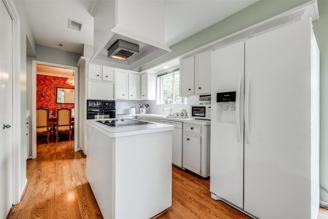 14110 Woodnook Dr, Houston, TX 77077 - kitchen with black appliances, a center island, light wood-style floors, light countertops, and white cabinetry