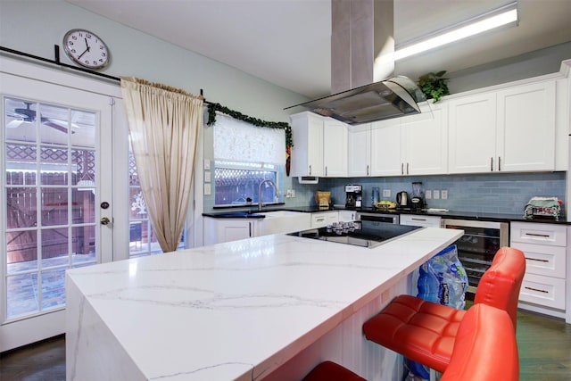 840 Threadneedle St E Unit 208, Houston, TX 77079 - kitchen with wine cooler, island exhaust hood, black electric cooktop, backsplash, and a center island