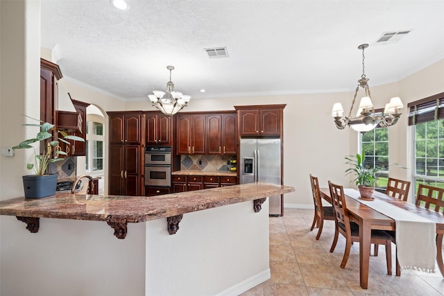 15590 Crown Oaks Dr, Montgomery, TX 77316 - kitchen with a chandelier, stainless steel appliances, arched walkways, a peninsula, and backsplash