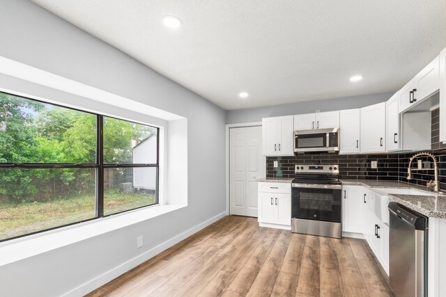 16234 Bowridge Ln, Houston, TX 77053 - kitchen with appliances with stainless steel finishes, light stone countertops, tasteful backsplash, light wood finished floors, and recessed lighting