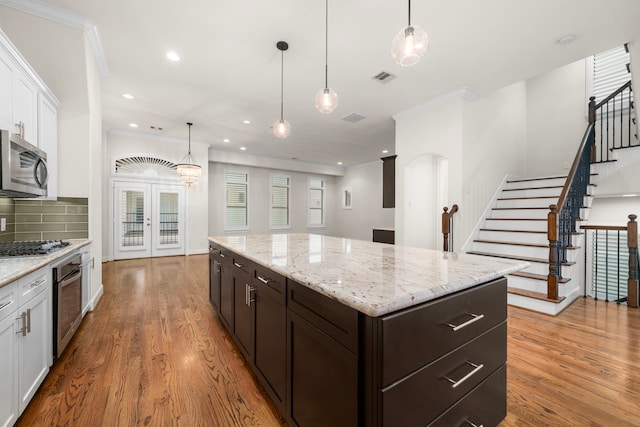 4314 Gibson St Unit B, Houston, TX 77007 - kitchen with appliances with stainless steel finishes, crown molding, white cabinetry, dark brown cabinets, and a center island