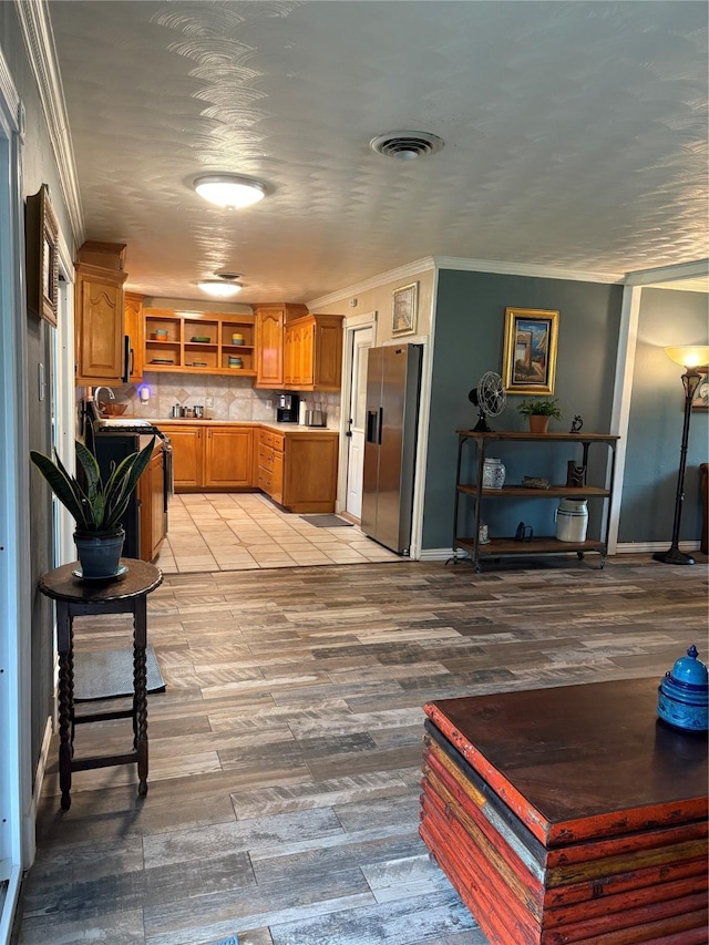 1205 Carmie St, Alvin, TX 77511 - kitchen with open shelves, stainless steel fridge with ice dispenser, brown cabinetry, crown molding, and light countertops