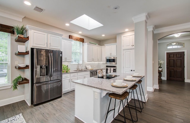 931 Shirkmere Rd, Houston, TX 77008 - kitchen with stainless steel appliances, arched walkways, a skylight, white cabinets, and a kitchen breakfast bar