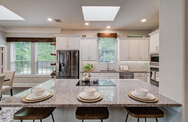 931 Shirkmere Rd, Houston, TX 77008 - kitchen featuring appliances with stainless steel finishes, a skylight, a kitchen bar, white cabinetry, and recessed lighting