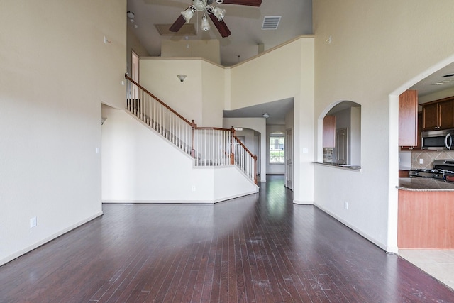 6533 Gray Birch Ln, Dickinson, TX 77539 - unfurnished living room with a ceiling fan, hardwood / wood-style floors, stairs, a towering ceiling, and arched walkways