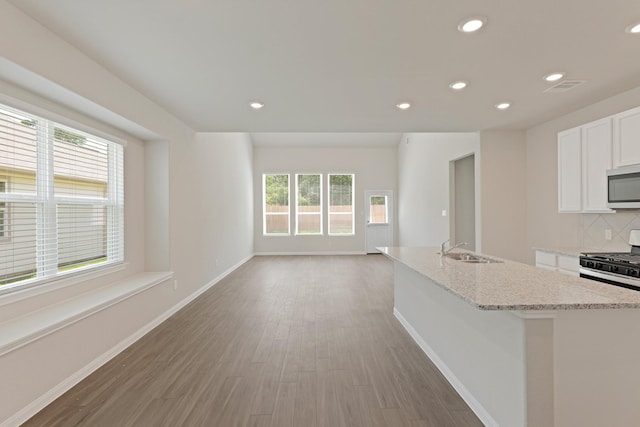 103 Black Bear Dr, Huntsville, TX 77320 - kitchen featuring range with gas stovetop, stainless steel microwave, recessed lighting, white cabinetry, and light stone countertops