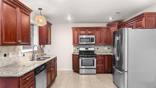 9643 Val Verde St, Houston, TX 77063 - kitchen with stainless steel appliances, reddish brown cabinets, decorative backsplash, hanging light fixtures, and recessed lighting