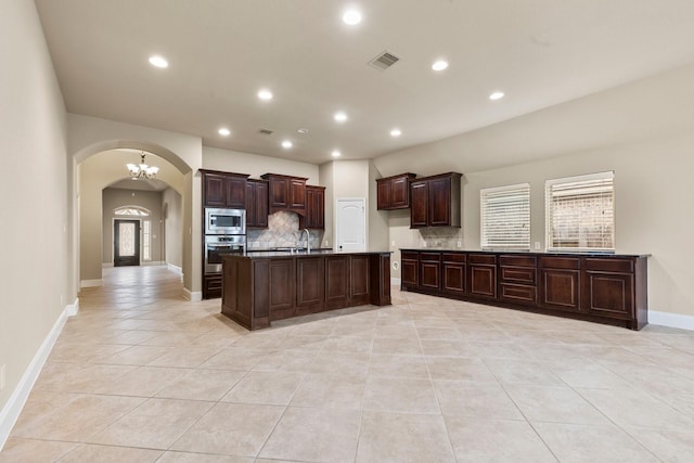 1215 Oxbow Crossing Ln, Rosenberg, TX 77471 - kitchen with stainless steel appliances, arched walkways, decorative backsplash, light tile patterned floors, and recessed lighting