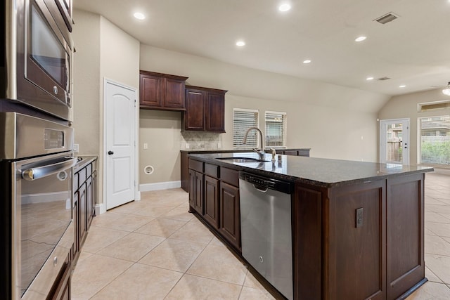 1215 Oxbow Crossing Ln, Rosenberg, TX 77471 - kitchen with stainless steel appliances, a kitchen island with sink, dark stone countertops, recessed lighting, and light tile patterned floors