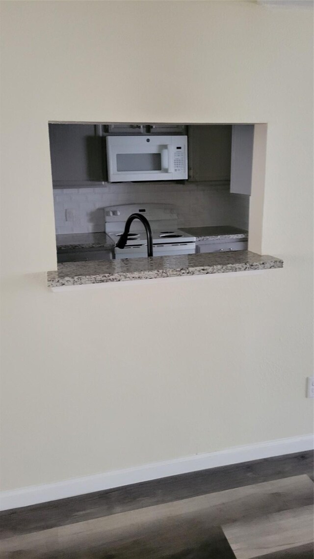 8367 Nairn St, Houston, TX 77074 - kitchen with white appliances, backsplash, wood finished floors, and light stone counters