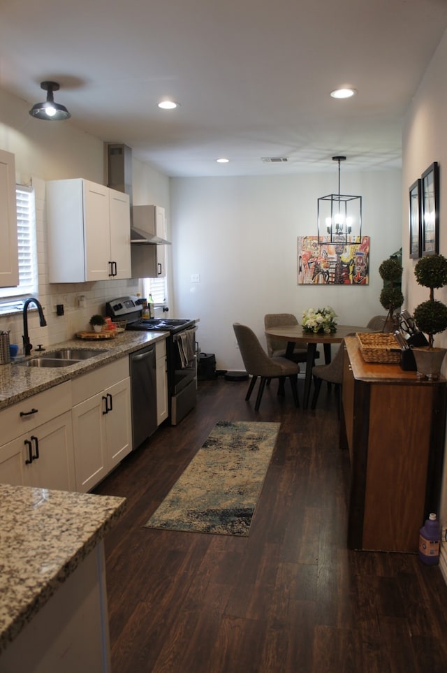 4217 Sterling St, Houston, TX 77051 - kitchen with appliances with stainless steel finishes, wall chimney range hood, dark wood finished floors, white cabinetry, and recessed lighting