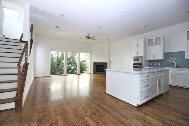 5711 Kansas, Houston, TX 77007 - kitchen featuring appliances with stainless steel finishes, a center island, a ceiling fan, decorative backsplash, and dark wood-style floors