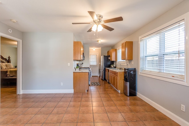 6335 Danshire Ct, Houston, TX 77049 - kitchen with stainless steel appliances, a ceiling fan, light countertops, light tile patterned floors, and brown cabinets
