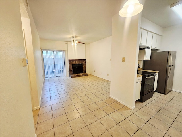 7950 N Stadium Dr Unit 191, Houston, TX 77030 - kitchen featuring black electric range oven, light tile patterned floors, white cabinets, a ceiling fan, and a brick fireplace
