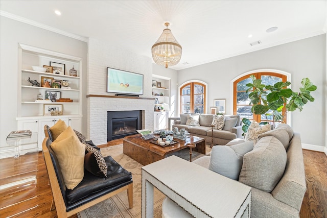 1712 Michigan St, Houston, TX 77006 - living room featuring built in features, a chandelier, wood finished floors, ornamental molding, and a fireplace