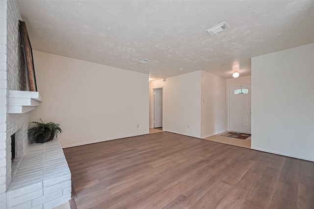 4330 Brookhead Trl, Houston, TX 77066 - unfurnished living room featuring wood finished floors, a fireplace, and a textured ceiling