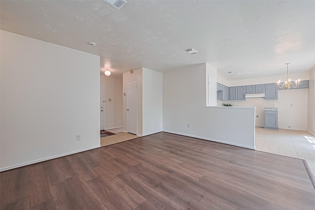 4330 Brookhead Trl, Houston, TX 77066 - unfurnished living room with wood finished floors, a chandelier, and a textured ceiling