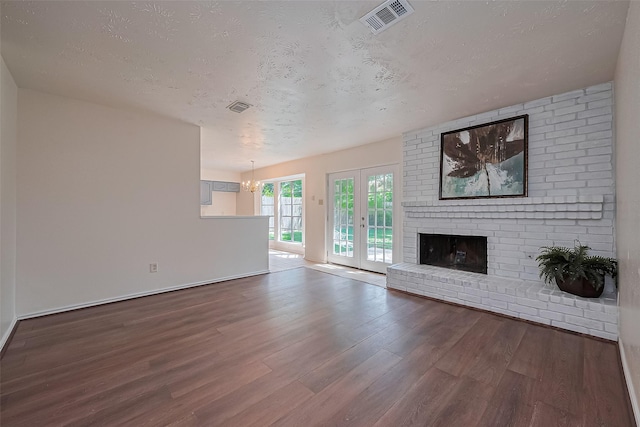 4330 Brookhead Trl, Houston, TX 77066 - unfurnished living room featuring wood finished floors, a textured ceiling, a brick fireplace, french doors, and a chandelier