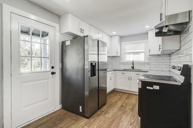 2003 Amelia St, Baytown, TX 77520 - kitchen with appliances with stainless steel finishes, under cabinet range hood, white cabinetry, decorative backsplash, and wood finished floors