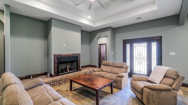1804 Esther Dr, Houston, TX 77088 - living room featuring a tray ceiling, ceiling fan, a fireplace, arched walkways, and light tile patterned floors