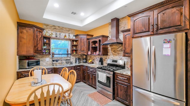 1804 Esther Dr, Houston, TX 77088 - kitchen with stainless steel appliances, wall chimney exhaust hood, open shelves, a tray ceiling, and light stone countertops