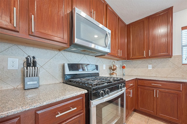 18231 Rexine Ln, Cypress, TX 77433 - kitchen with appliances with stainless steel finishes, brown cabinets, light stone counters, tasteful backsplash, and a textured ceiling