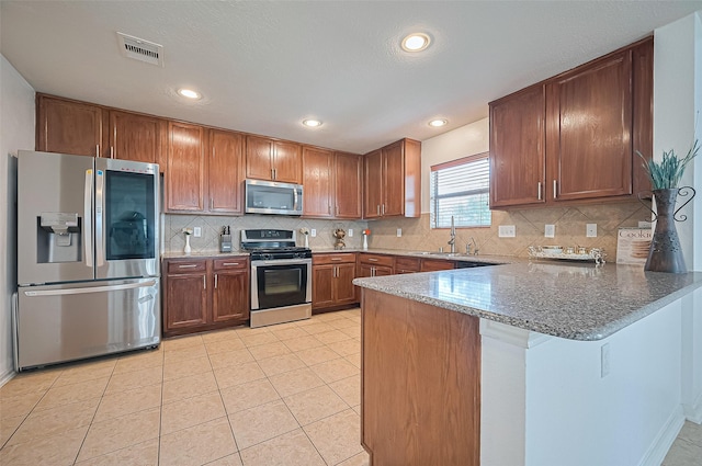 18231 Rexine Ln, Cypress, TX 77433 - kitchen featuring stainless steel appliances, a peninsula, brown cabinets, light stone countertops, and recessed lighting