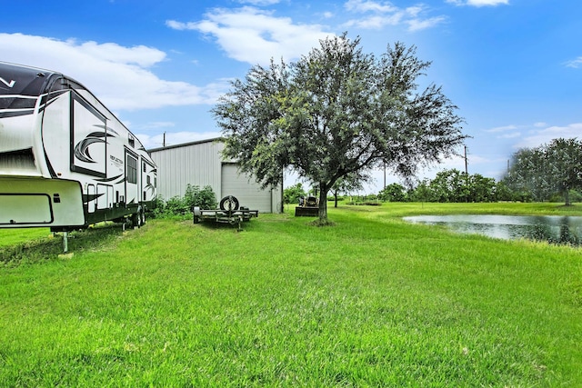 7403 Falcon Dr, Brookshire, TX 77423 - view of grassy yard featuring a water view, a garage, and an outbuilding
