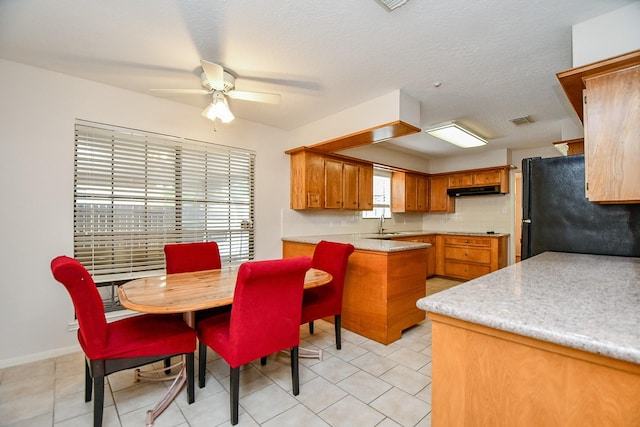 11103 Pembridge Dr, Houston, TX 77071 - kitchen with freestanding refrigerator, a ceiling fan, light countertops, brown cabinetry, and light tile patterned flooring