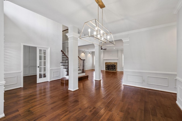 15902 Ivy Bridge Ln, Houston, TX 77095 - unfurnished living room featuring ornate columns, stairs, a decorative wall, dark wood-style floors, and french doors