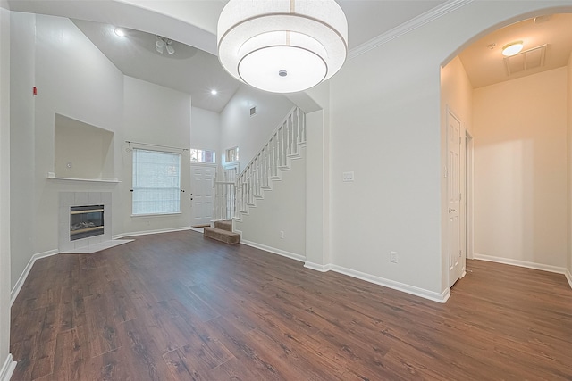 2710 Grants Lake Blvd Unit T6, Sugar Land, TX 77479 - unfurnished living room featuring dark wood finished floors, arched walkways, stairs, a towering ceiling, and crown molding