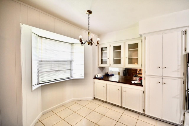11931 Tanager St, Houston, TX 77072 - kitchen with light tile patterned floors, a chandelier, dark countertops, glass insert cabinets, and pendant lighting