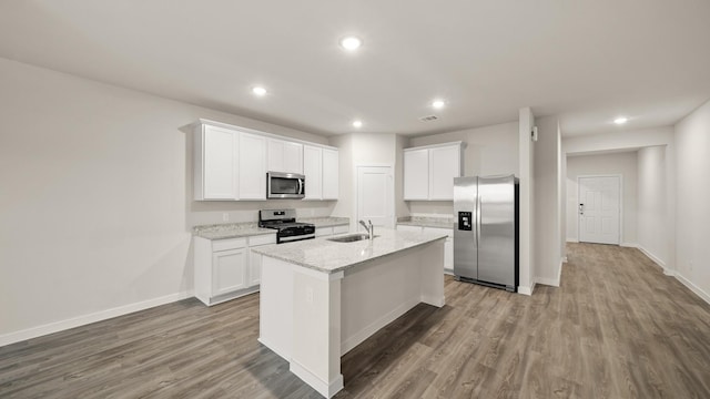 25021 Pomegranate Pl, Montgomery, TX 77316 - kitchen with stainless steel appliances, recessed lighting, wood finished floors, white cabinets, and an island with sink