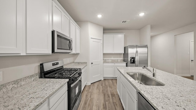 25021 Pomegranate Pl, Montgomery, TX 77316 - kitchen with appliances with stainless steel finishes, light wood finished floors, white cabinetry, recessed lighting, and light stone counters