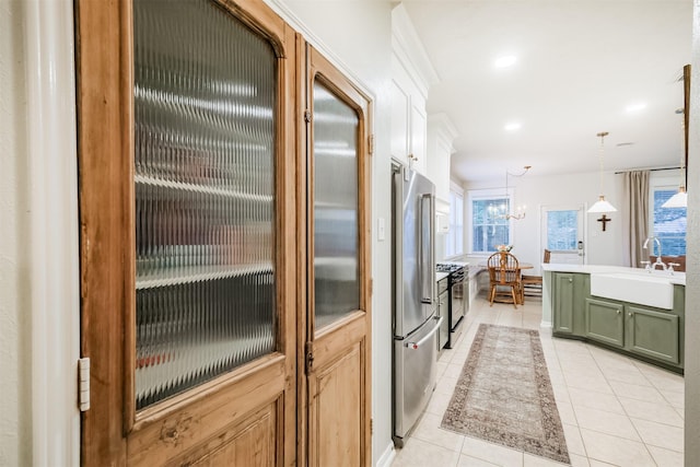 703 Rock Creek Ct, Rosenberg, TX 77469 - kitchen with green cabinets, gas range oven, light tile patterned floors, freestanding refrigerator, and light countertops