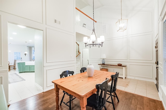 703 Rock Creek Ct, Rosenberg, TX 77469 - dining room featuring a chandelier, a decorative wall, wood-type flooring, a towering ceiling, and stairs