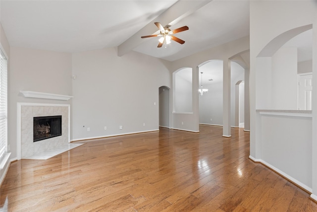 16306 Ancient Forest Dr, Humble, TX 77346 - unfurnished living room with a ceiling fan, a tiled fireplace, wood-type flooring, and arched walkways